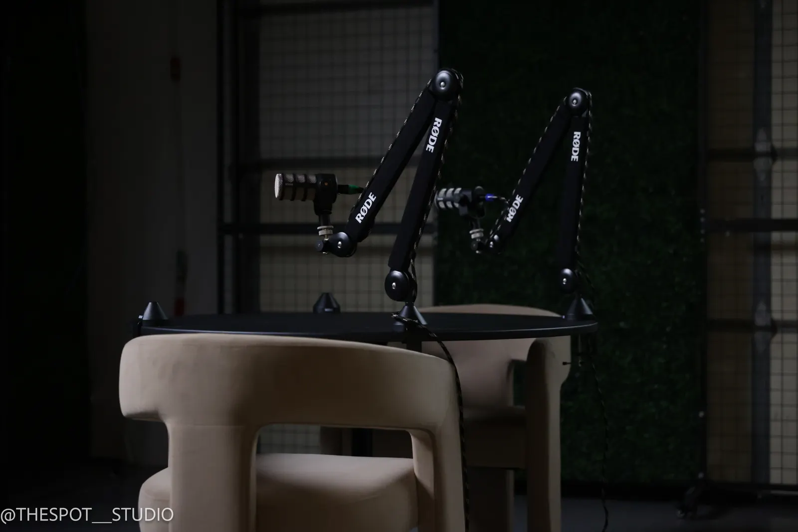Microphone arms over the table with the greenery wall in the Garage Room
