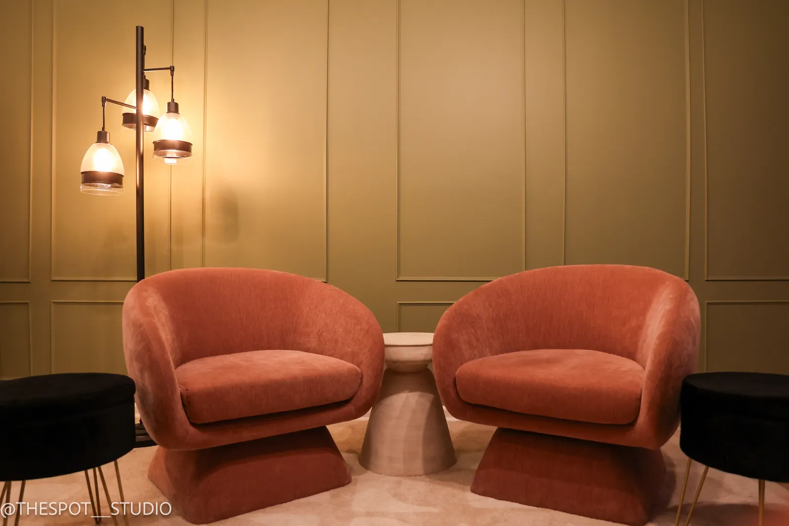 Two lounge chairs and floor lamp against the Primary Studio green wall