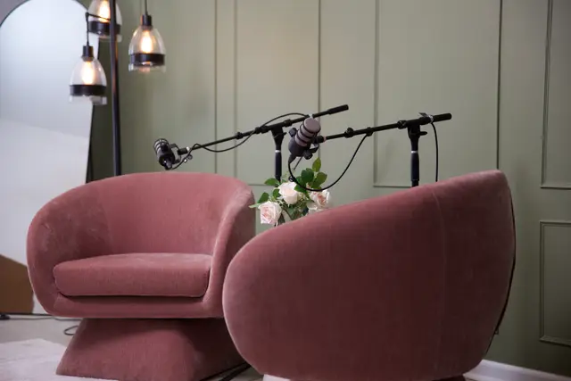 Rose lounge chairs with boom microphones against the green wall in the Primary Studio