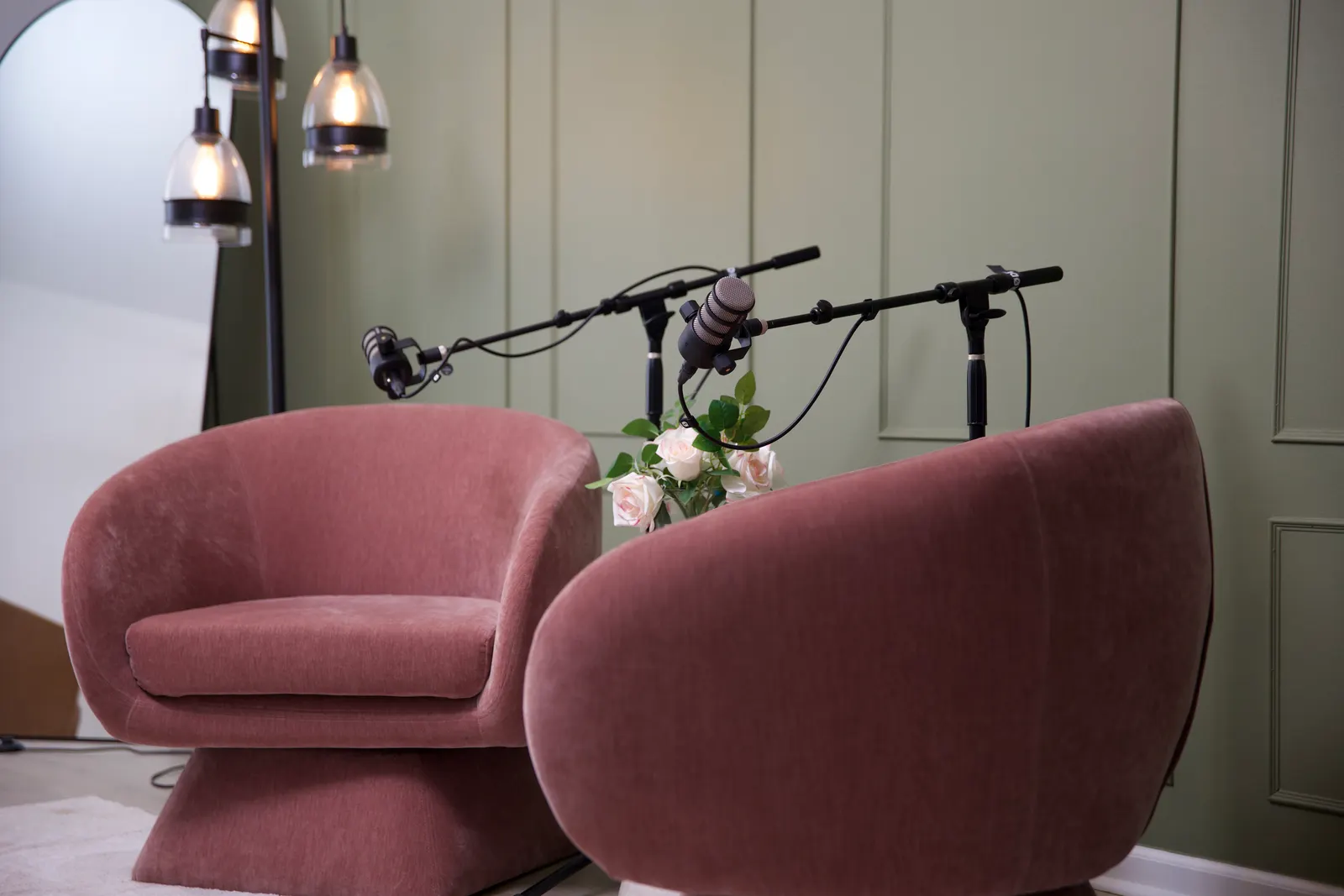 Rose lounge chairs with boom microphones against the green wall in the Primary Studio